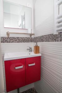 een badkamer met een rode wastafel en een spiegel bij Studio London & Studio Chalet in Pannes