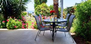 einen Glastisch mit vier Stühlen und Blumen in der Unterkunft CORAL BAY suite Cyprus in Coral Bay
