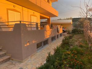 uma casa amarela com uma escada ao lado de um quintal em Ksamil Harmony Studios em Ksamil