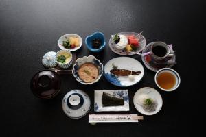 Atarashiya Ryokan في Tenkawa: طاولة مع أطباق من الطعام وأكواب من الشاي