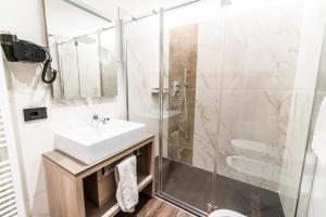 a bathroom with a shower, sink, and mirror at Lady Maria Hotel Wellness & Resort in Fondo