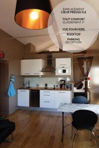 una cocina con armarios blancos y una mesa con sillas. en Les Toits de Lyon, en Lyon
