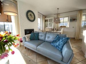 a blue couch in a living room with a clock on the wall at Strandperle 264 mit Sauna und Kamin in Julianadorp