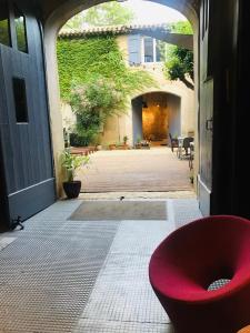einem roten Stuhl, der in der Tür eines Hauses sitzt in der Unterkunft Le Voyageur - Chambres d'Hôtes in Olonzac