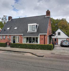 een rood bakstenen huis met een zwart dak bij Vakantie appartement de Havezate in Roden