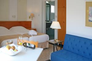 a hotel room with two beds and a bowl of fruit on a table at Chrielka Hotel in Limassol