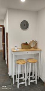 a kitchen counter with two stools and a clock on the wall at Casa de la Abuela en el Camino de Santiago a Finiesterre in Negreira