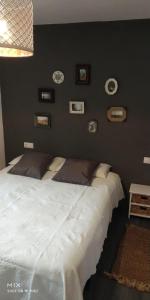 a bedroom with a large white bed with pictures on the wall at Casa de la Abuela en el Camino de Santiago a Finiesterre in Negreira