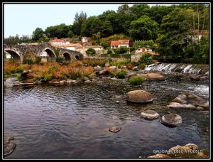 a river with a bridge and some rocks and trees at Casa de la Abuela en el Camino de Santiago a Finiesterre in Negreira