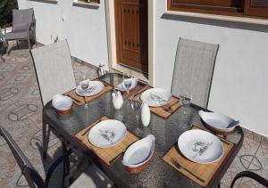 a wooden table with plates and glasses on it at Anna - Maria Luxury Suite in Skala Rachoniou