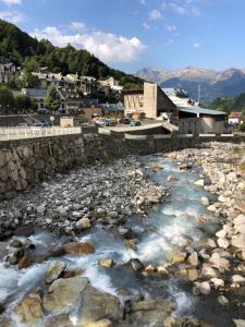 a river with rocks in front of a town at Les Sorbiers Barèges in Barèges