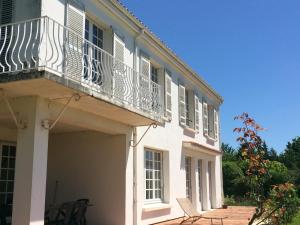 um edifício branco com uma varanda e cadeiras num pátio em La Maison Blanche em Saint-Jean-dʼAngély