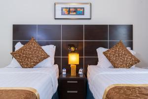 a hotel room with two beds and a lamp at Platinum Seventy in Jeddah