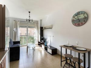 uma sala de estar com uma mesa e um relógio na parede em Belvilla by OYO Apartment in Roquetas de Mar em Aguadulce