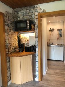 a kitchen with a stone wall with a microwave at Haus Sonnenschein in Stafstedt