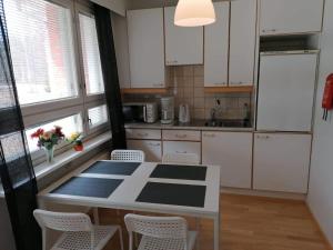 - une cuisine avec des placards blancs, une table et des chaises dans l'établissement Hotelli Ravintola Tiilikka, à Rautavaara