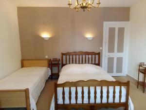 a bedroom with two beds and a chandelier at La Mare aux 3 Diables in Fresney-le-Vieux