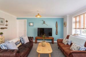 a living room with brown leather couches and a table at Beach Cottage in Lytham St Annes