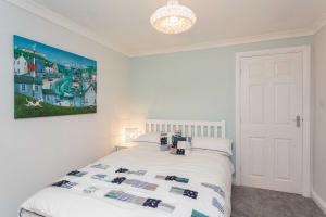 a bedroom with a white bed with a painting on the wall at Beach Cottage in Lytham St Annes