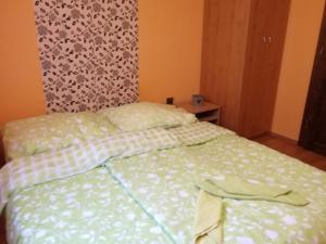a bedroom with a bed with a green and white comforter at CHATA NATAŠA in Dedinky