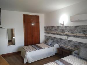 a bedroom with two beds and a brick wall at Hostal El Rincón - Casa Marcos in Yepes