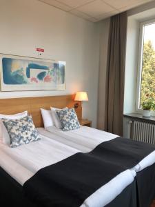 1 dormitorio con 1 cama grande con almohadas y ventana en Grand Hotel Falkenberg, en Falkenberg