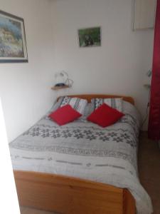 - une chambre avec un lit et 2 oreillers rouges dans l'établissement La Collinette, à Saint-Laurent-du-Cros