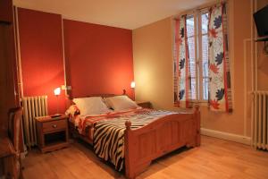 a bedroom with a bed with red walls and a window at Hotel du Cygne in Beauvais