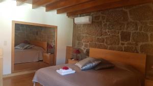 a bedroom with two beds and a stone wall at Olhares do Douro "A casa do Avô Zé" in Foz do Sabor
