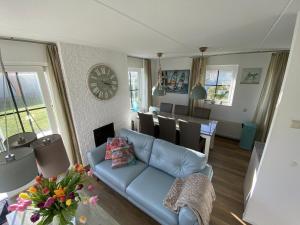 a living room with a blue couch and a clock on the wall at Strandperle 44 in Julianadorp