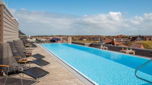 a swimming pool on top of a building with chairs at Die Sandburg in Langeoog