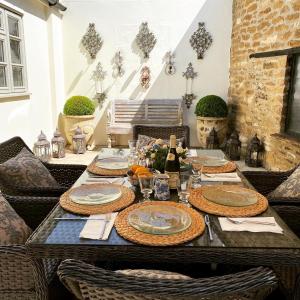 una mesa con platos y vasos encima en Jasmine Cottage, en Chipping Campden