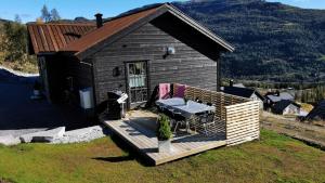 a small cabin with a deck with a table on it at Timblalodgen in Sogndal