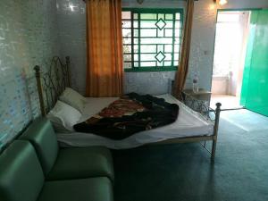 een bed in een kamer met een bank en een raam bij Nathia Heights Hotel in Bāzār