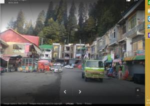 a street in a town with cars and buildings at Nathia Heights Hotel in Bāzār