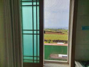 - une fenêtre dans une chambre avec vue sur un champ dans l'établissement Feeling Good House, à Jeju
