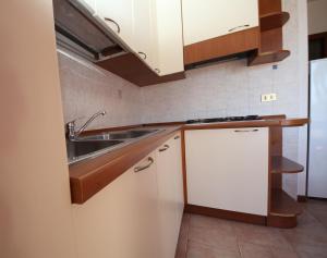 a kitchen with white cabinets and a sink at Villa Gloria appartamento E01 in Rosolina Mare