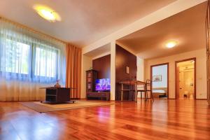 a living room with a hard wood floor and a television at Predeal Fine Apartaments Clabucet in Predeal
