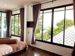 a bedroom with a bed and large windows at Magic House - No Pets Allowed in Chumphon