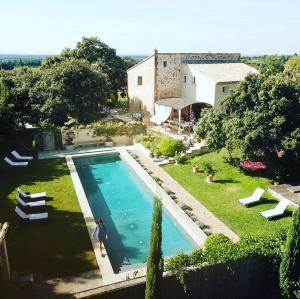 a person standing next to a swimming pool next to a house at La bergerie de Nano in Beaumes-de-Venise