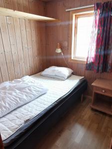 Cama en habitación de madera con ventana en Ørterstølen Hytter en Gol