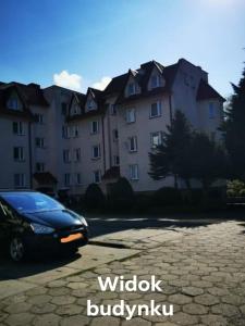 une voiture noire garée devant un grand bâtiment dans l'établissement Apartament Magdalenka, à Władysławowo