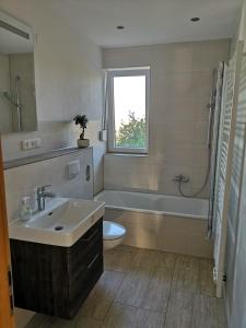 La salle de bains est pourvue d'un lavabo, d'une baignoire et de toilettes. dans l'établissement Ferienwohnung "Burgpanorama" in der Südpfalz, à Leinsweiler