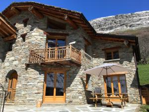 a stone house with a balcony and an umbrella at La Datcha*** 4-5 personnes in Bonneval-sur-Arc