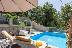 a swimming pool with chairs and an umbrella at Casa do Progo in Ponte de Lima