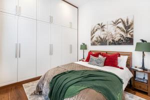 a bedroom with white cabinets and a bed with red pillows at Buckingham & Lloyds in London