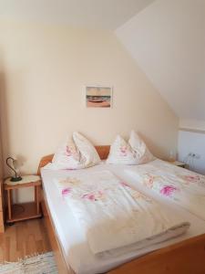 ein Bett mit weißer Bettwäsche und rosa Blumen darauf in der Unterkunft Gästehaus Anna in Unterlamm
