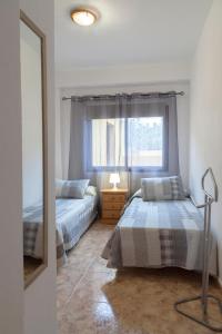 2 camas en un dormitorio con espejo y ventana en Apt Aguedita 3 dorm terraza y vistas al mar y la montaña, en La Frontera