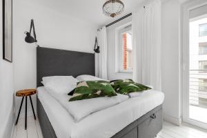 Dormitorio blanco con cama con almohadas verdes en Happy Stay Tartaczna Residence III, en Gdansk