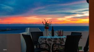 パレオコラにあるPanoramio Paleochora Apartmentsの夕日を眺めながらバルコニーに置かれたワインのボトルが置かれたテーブル